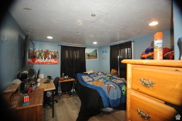 bedroom with wood finished floors, recessed lighting, and a textured ceiling