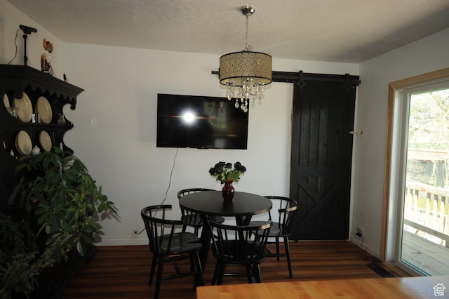 dining area featuring a barn door, wood finished floors, baseboards, and a notable chandelier