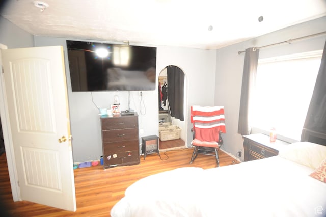 bedroom featuring wood finished floors and arched walkways