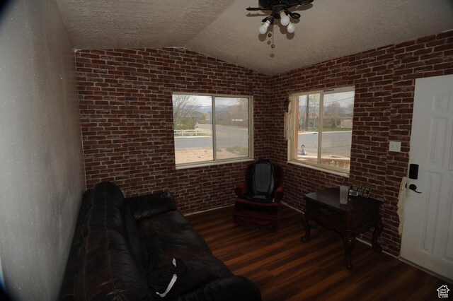 living room featuring a ceiling fan, wood finished floors, a textured ceiling, brick wall, and lofted ceiling