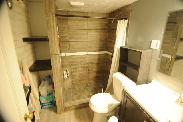 full bathroom featuring wood finished floors, vanity, a shower stall, and toilet