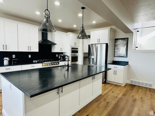 2747 S Country Club Way, Garden City, UT 84028 - kitchen featuring stainless steel appliances, light wood-style flooring, dark countertops, recessed lighting, and wall chimney range hood