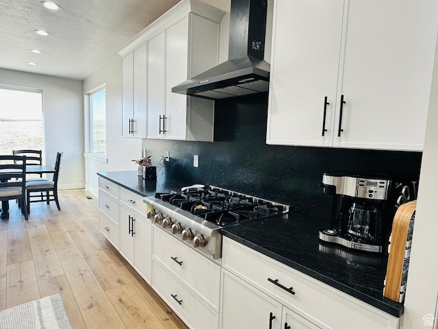 2747 S Country Club Way, Garden City, UT 84028 - kitchen with wall chimney range hood, stainless steel gas stovetop, decorative backsplash, white cabinets, and light wood-style flooring