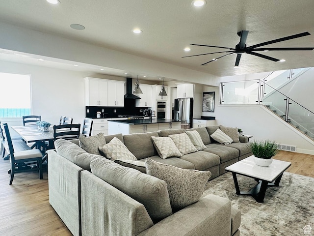 2747 S Country Club Way, Garden City, UT 84028 - living room with recessed lighting, light wood-style floors, a ceiling fan, stairs, and a textured ceiling