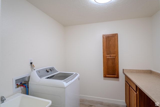 2976 E Saddle Rock Rd, Eagle Mountain, UT 84005 - laundry room with light wood finished floors, a sink, baseboards, washer / clothes dryer, and cabinet space