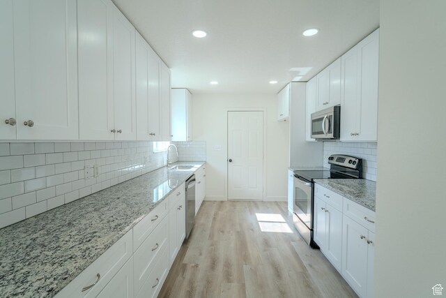 2976 E Saddle Rock Rd, Eagle Mountain, UT 84005 - kitchen featuring backsplash, light stone countertops, appliances with stainless steel finishes, and a sink