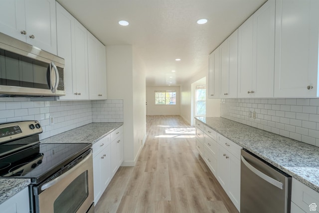 2976 E Saddle Rock Rd, Eagle Mountain, UT 84005 - kitchen with white cabinets, light wood-type flooring, appliances with stainless steel finishes, and baseboards