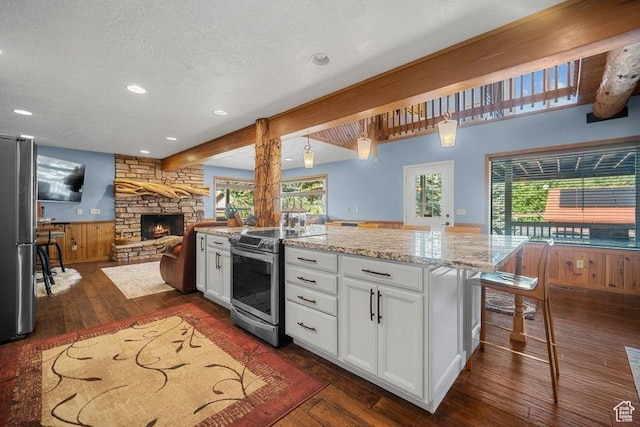 kitchen with light stone counters, stainless steel appliances, a fireplace, a textured ceiling, and white cabinetry