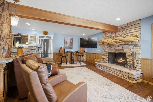 835 E Mountain View Dr, Pine Valley, UT 84781 - living area featuring wood finished floors, a stone fireplace, beam ceiling, and a wainscoted wall