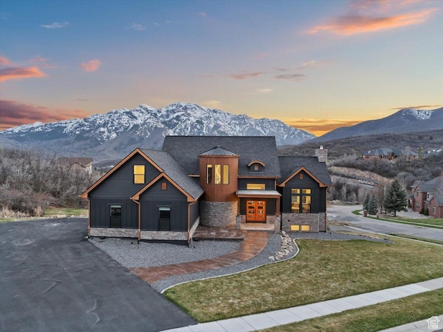 view of front of property with a mountain view, stone siding, board and batten siding, and a front yard
