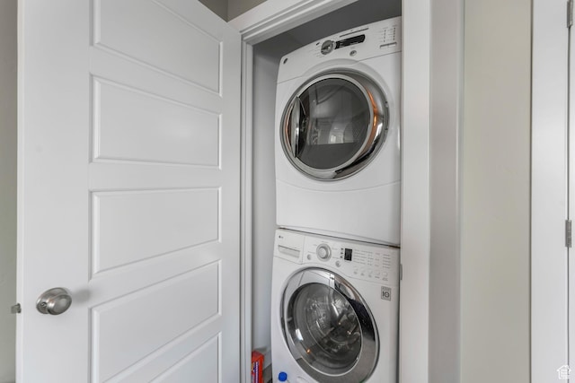 clothes washing area featuring stacked washer and clothes dryer and laundry area