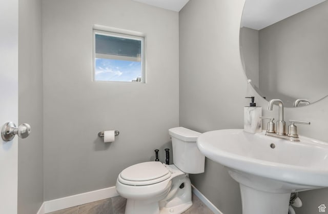 half bathroom featuring baseboards, a sink, and toilet