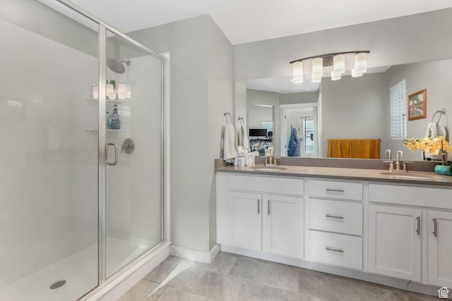 bathroom with baseboards, double vanity, a stall shower, and a sink