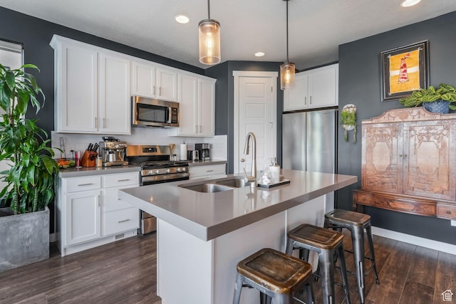 kitchen featuring a sink, a breakfast bar, backsplash, appliances with stainless steel finishes, and dark wood-type flooring