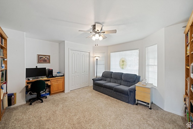 office featuring light carpet, a ceiling fan, and baseboards