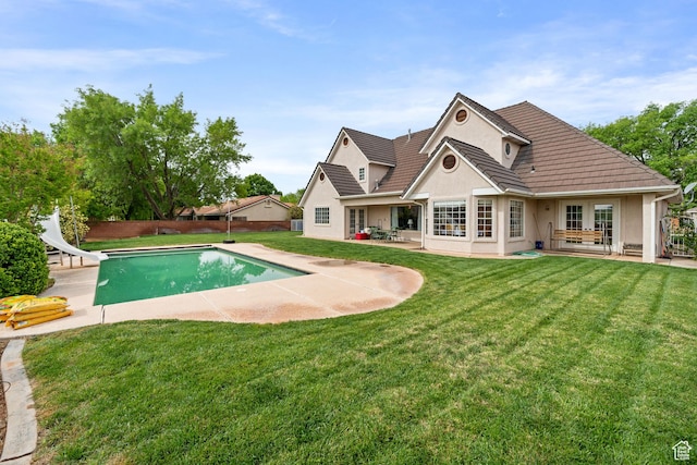 view of pool with fence, a yard, a patio, a fenced in pool, and a water slide