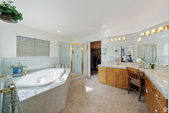 bathroom featuring a walk in closet, a tub with jets, vanity, and a stall shower