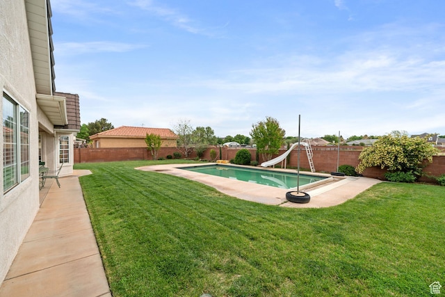 view of pool featuring a fenced in pool, a water slide, a fenced backyard, and a lawn