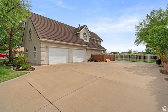view of side of home with fence, a tiled roof, driveway, and stucco siding