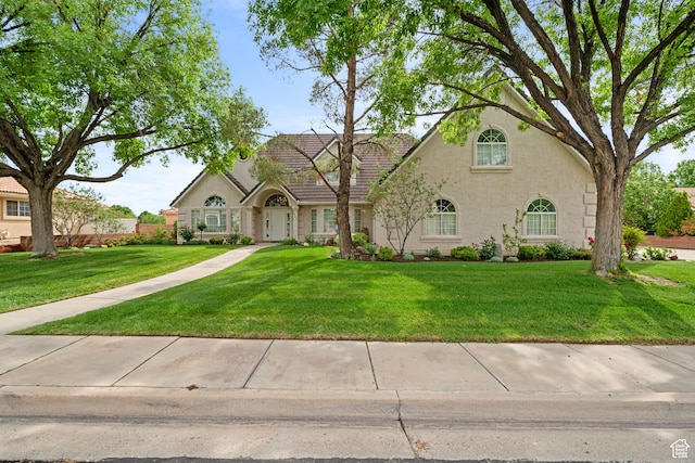 view of front of home featuring a tiled roof, a front yard, and stucco siding
