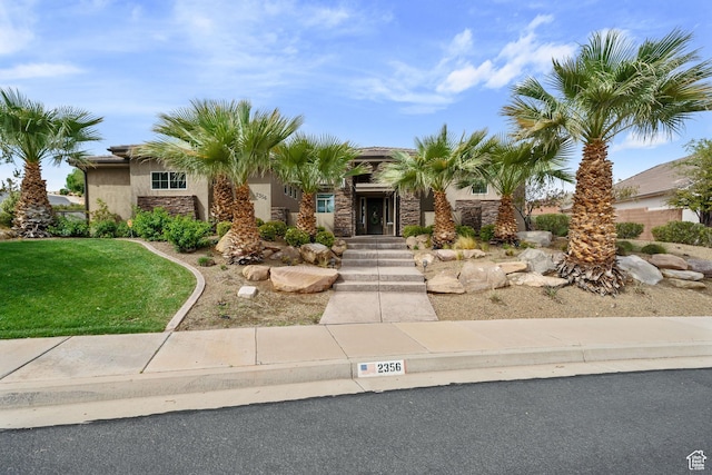 view of front of house with stone siding, a front lawn, and stucco siding