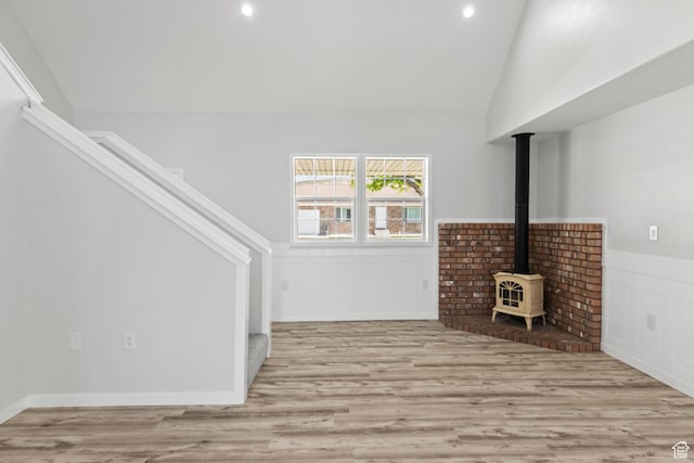 604 S Desert Willow Ln, Salina, UT 84654 - unfurnished living room featuring a wood stove, stairway, a wainscoted wall, vaulted ceiling, and wood finished floors