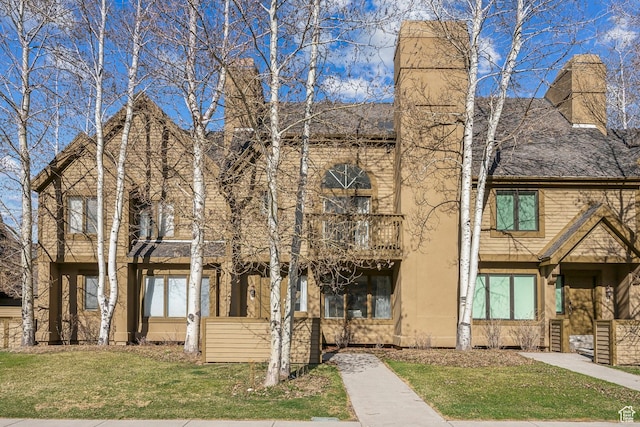 multi unit property featuring stucco siding, a front lawn, and a balcony