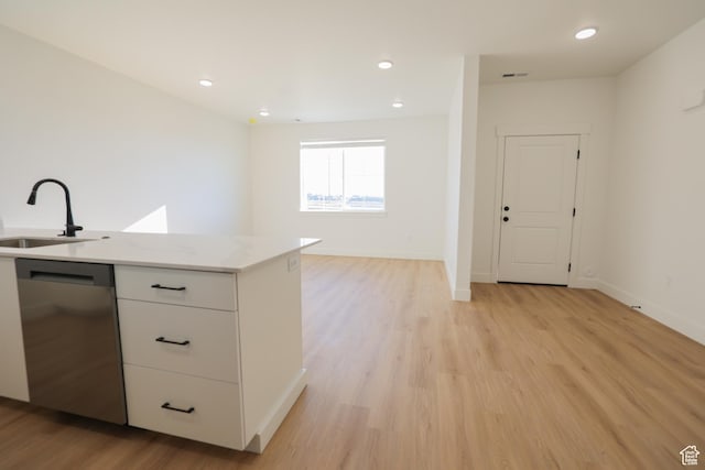 kitchen featuring white cabinets, dishwasher, a sink, light wood-style flooring, and open floor plan