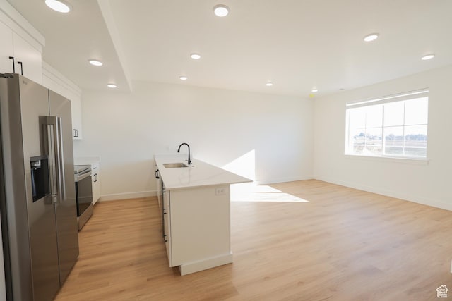 kitchen with white cabinets, stainless steel appliances, a sink, light wood-type flooring, and baseboards