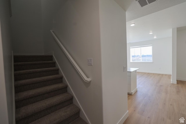 staircase with visible vents, baseboards, wood finished floors, and recessed lighting