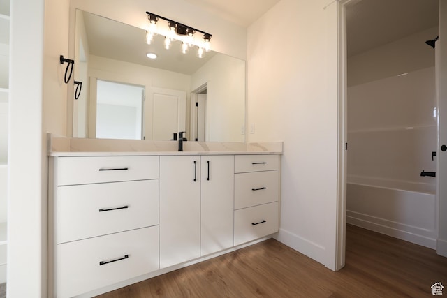 full bath featuring baseboards, vanity, and wood finished floors