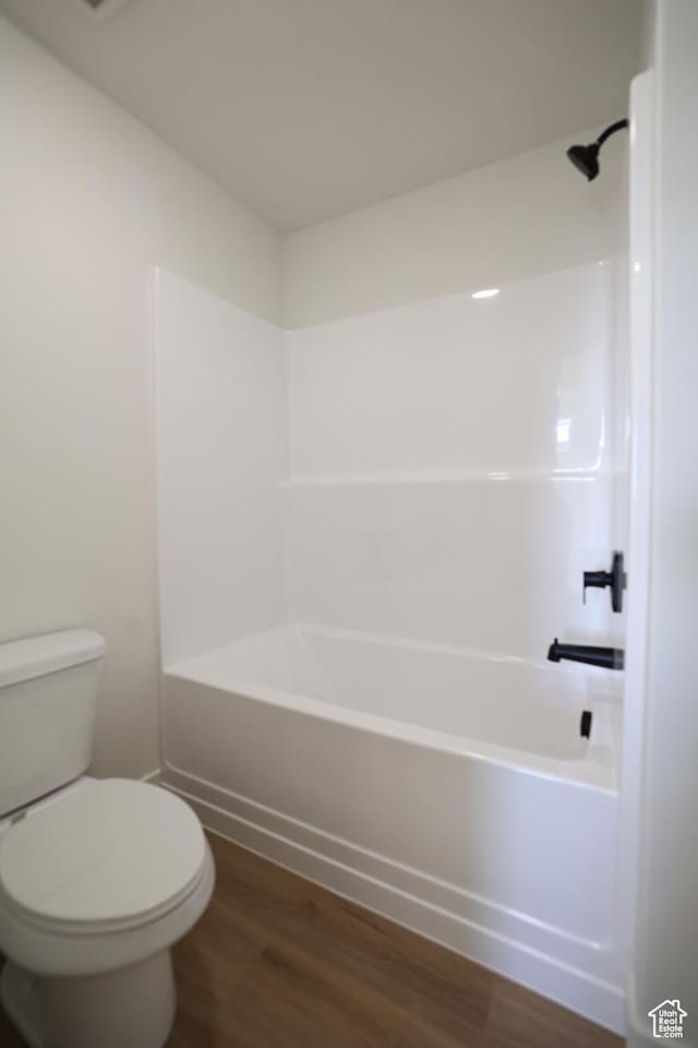 bathroom with toilet, wood finished floors, and shower / bath combination