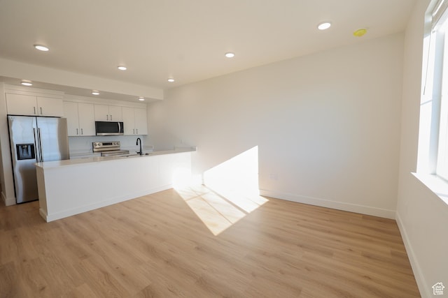 kitchen featuring light wood-type flooring, stainless steel appliances, a sink, and recessed lighting