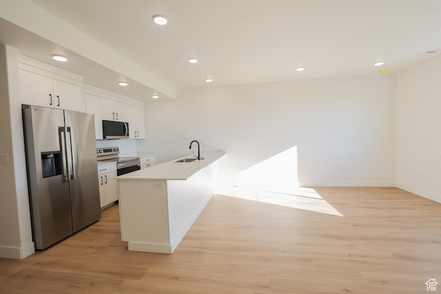 kitchen with a sink, stainless steel appliances, baseboards, white cabinets, and a peninsula