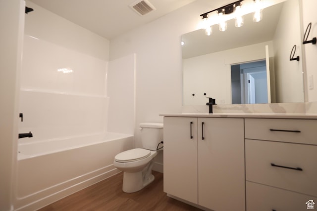 full bath featuring toilet, visible vents, wood finished floors, washtub / shower combination, and vanity