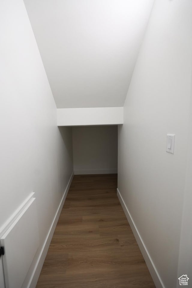 hall with lofted ceiling, baseboards, and wood finished floors