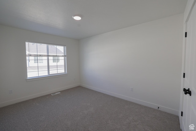spare room with visible vents, baseboards, and carpet flooring