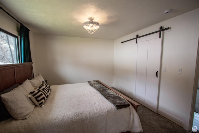 64 Winding Way, Logan, UT 84321 - carpeted bedroom with a barn door, baseboards, and a notable chandelier