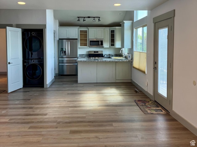 1126 E Bench View Dr N, Ogden, UT 84404 - kitchen with stainless steel appliances, a peninsula, light wood-type flooring, glass insert cabinets, and stacked washer and clothes dryer