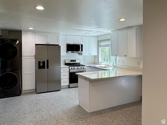 1126 E Bench View Dr N, Ogden, UT 84404 - kitchen with a textured ceiling, a sink, stacked washing maching and dryer, stainless steel appliances, and a peninsula