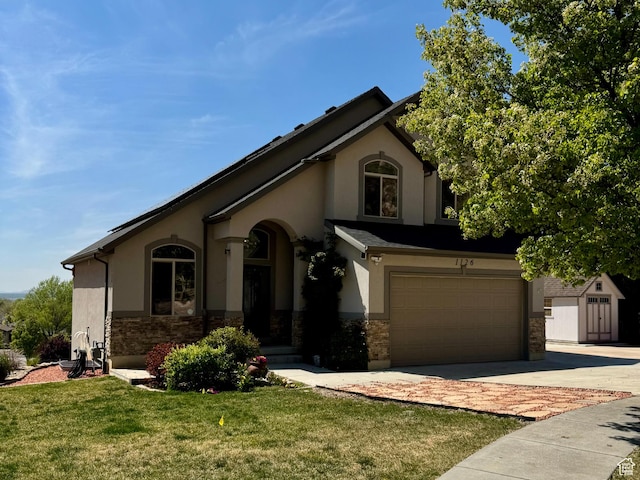 1126 E Bench View Dr N, Ogden, UT 84404 - view of front facade with concrete driveway, a front lawn, stone siding, a garage, and stucco siding
