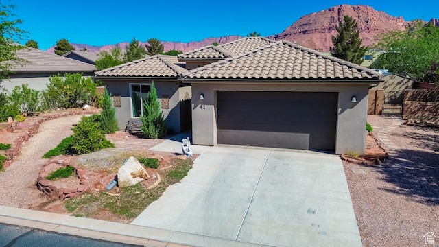 mediterranean / spanish home featuring a tiled roof, a mountain view, driveway, a garage, and stucco siding