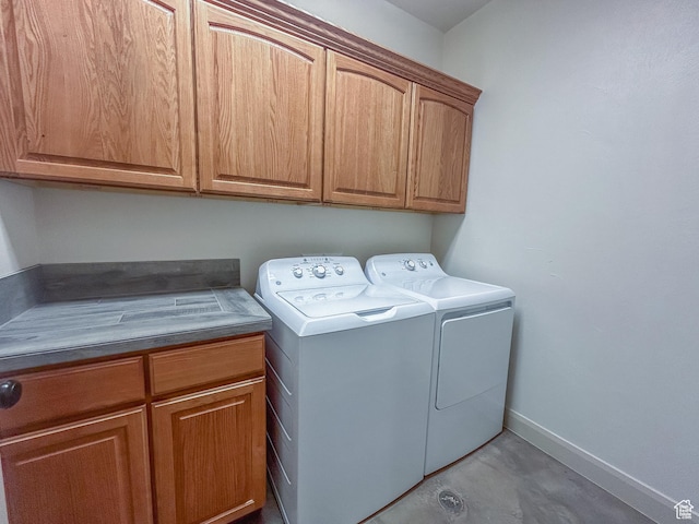 clothes washing area featuring cabinet space, washing machine and clothes dryer, and baseboards