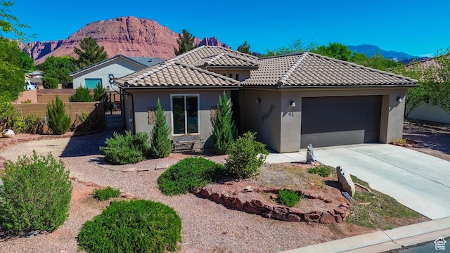 view of front of home featuring stucco siding, a mountain view, fence, and a garage