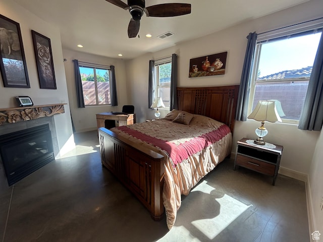 bedroom featuring a ceiling fan, a glass covered fireplace, baseboards, visible vents, and recessed lighting