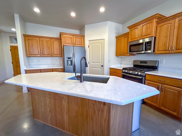 kitchen with a sink, brown cabinets, appliances with stainless steel finishes, and a center island with sink