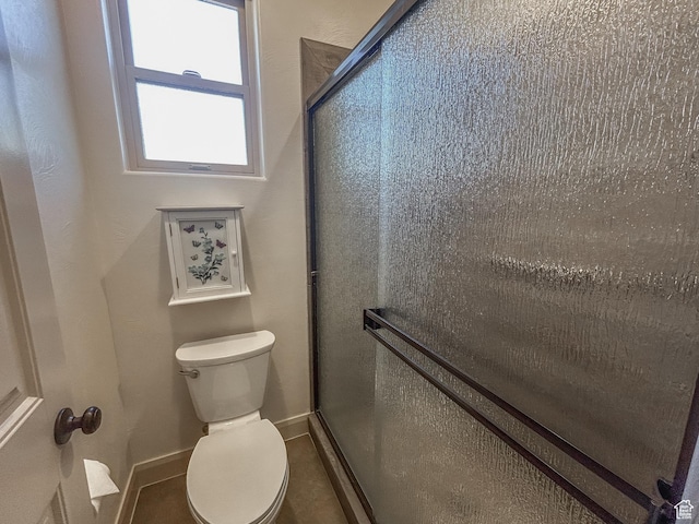 bathroom featuring baseboards, a shower stall, and toilet
