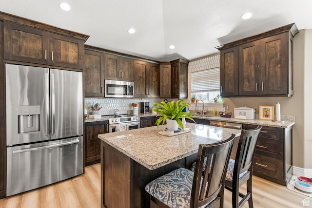1317 N Providence Way, Tooele, UT 84074 - kitchen featuring stainless steel appliances, a sink, light wood-type flooring, dark brown cabinetry, and light stone counters