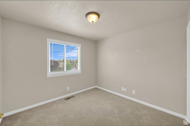 empty room with baseboards, a textured ceiling, visible vents, and carpet