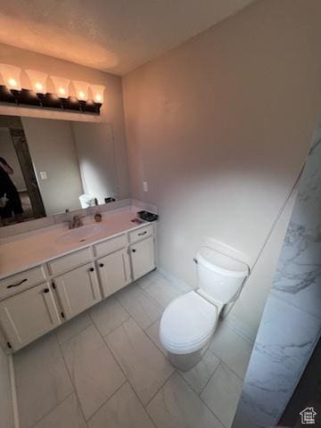 bathroom with marble finish floor, vanity, and toilet